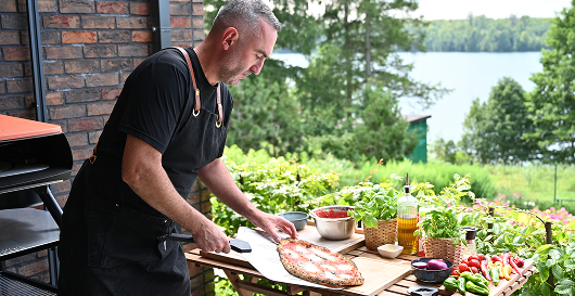 Mężczyzna przyrządzający pizzę w ogrodzie