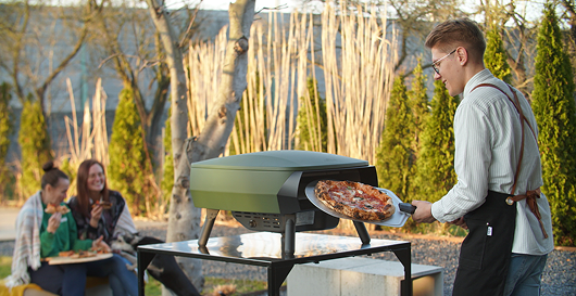 Mężczyzna przyrządzający pizzę w ogrodzie